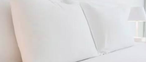 Una cama con ropa de cama y almohadas blancas.