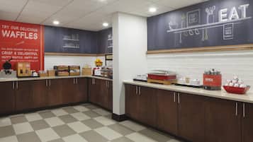 Un área de cocina con estaciones de gofres, una máquina de café y un tazón de avena.