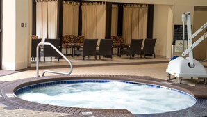 Een zone met een hottub, pooltafel en stoelen, een rolstoeltoegankelijke lift en een bord met veiligheidsinstructies.