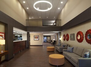 A hotel lobby with a reception desk, seating area, and a staircase leading to an upper level. - Hampton Inn Charleston-Southridge (Charleston)