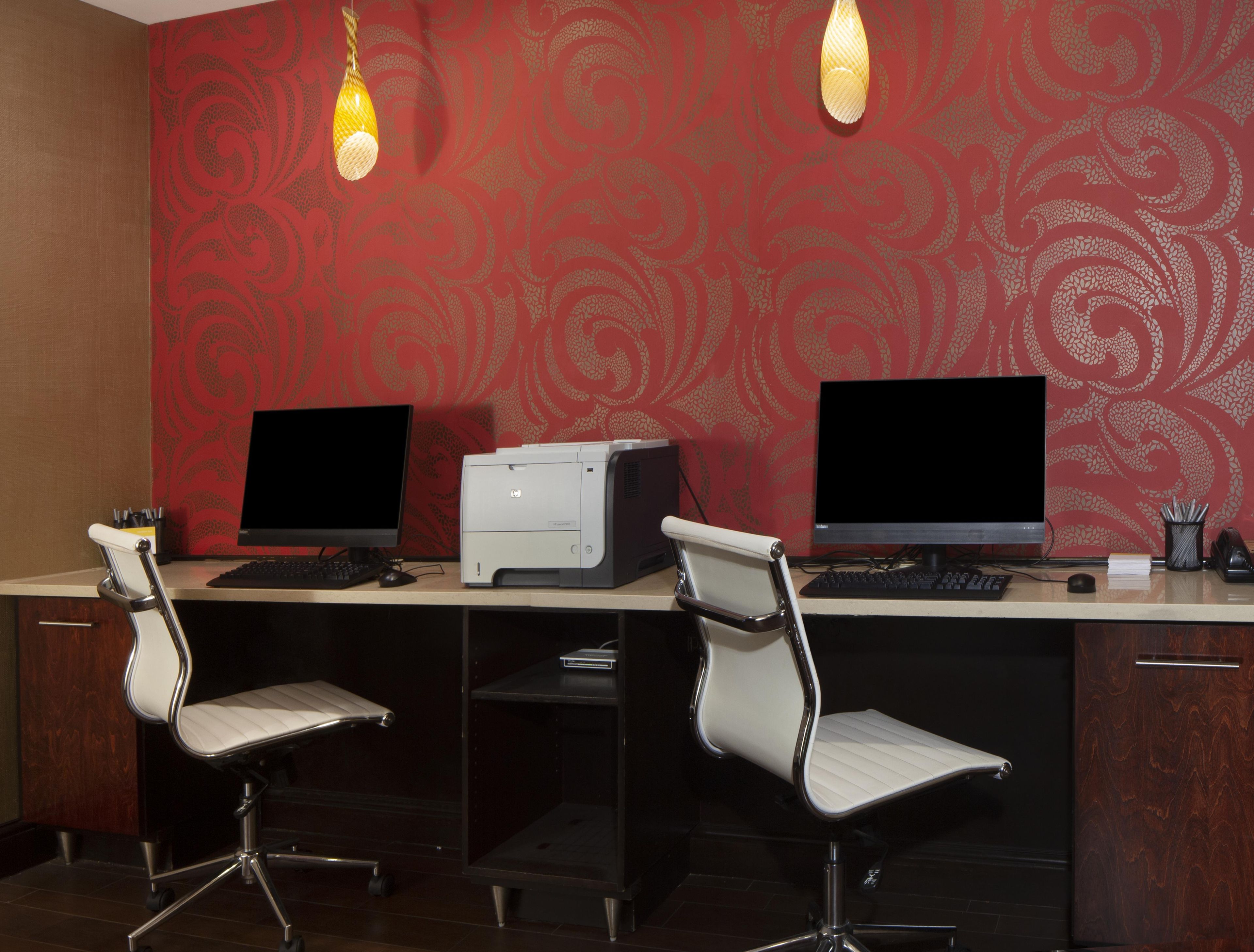 Un espacio de trabajo con dos monitores, una impresora y dos sillas de oficina.