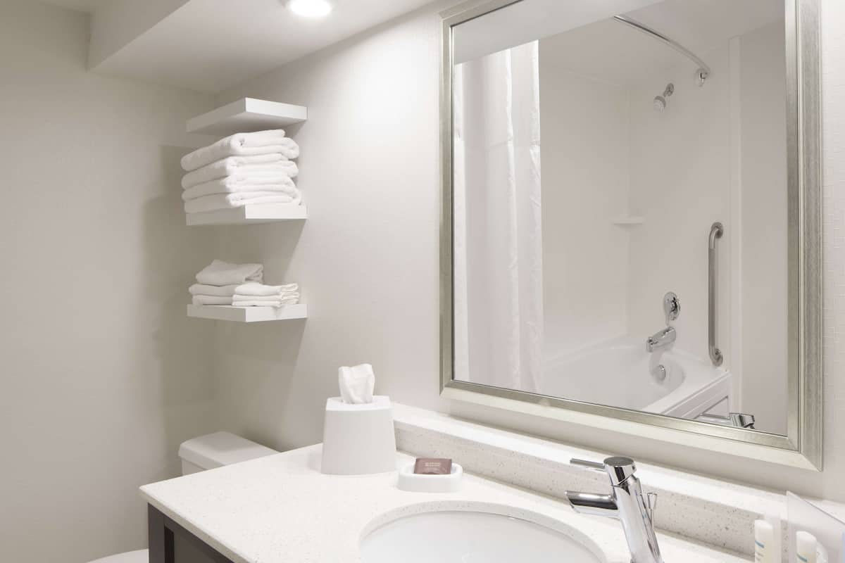 Ein modernes Badezimmer mit einem weißen Waschbecken, einem Spiegel und einer Dusche.