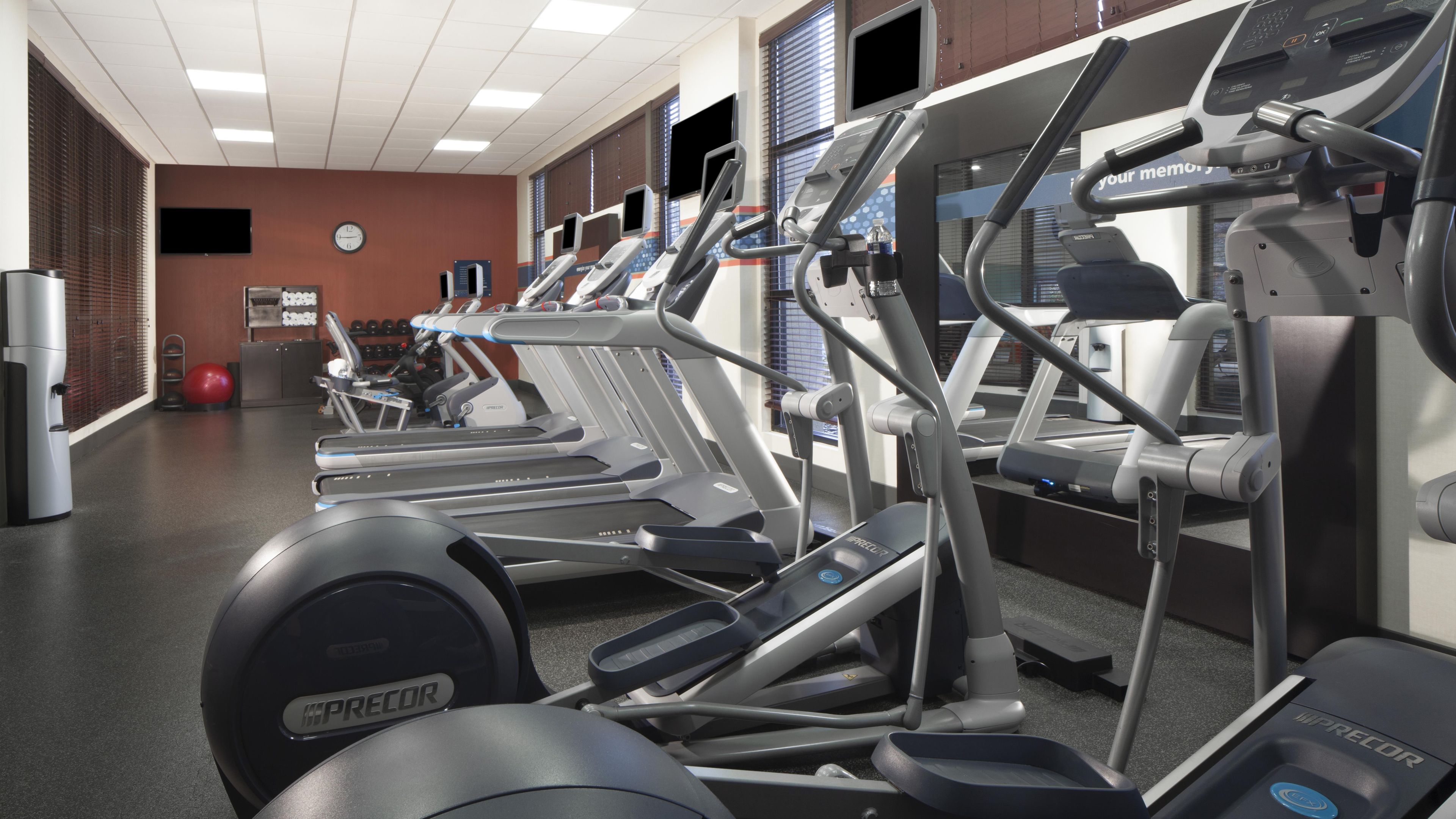 A gym with multiple treadmills, ellipticals, and weight machines.