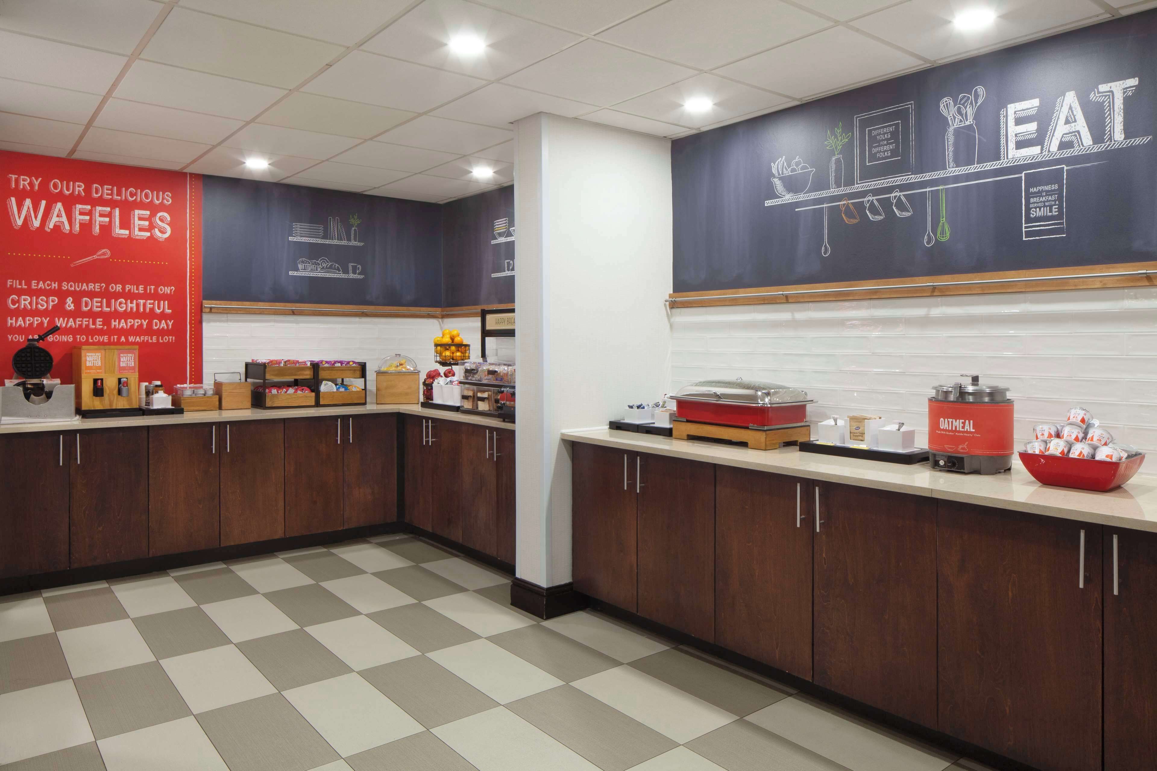 A kitchen area with waffle-making equipment, a waffle station, and a counter with various food items.