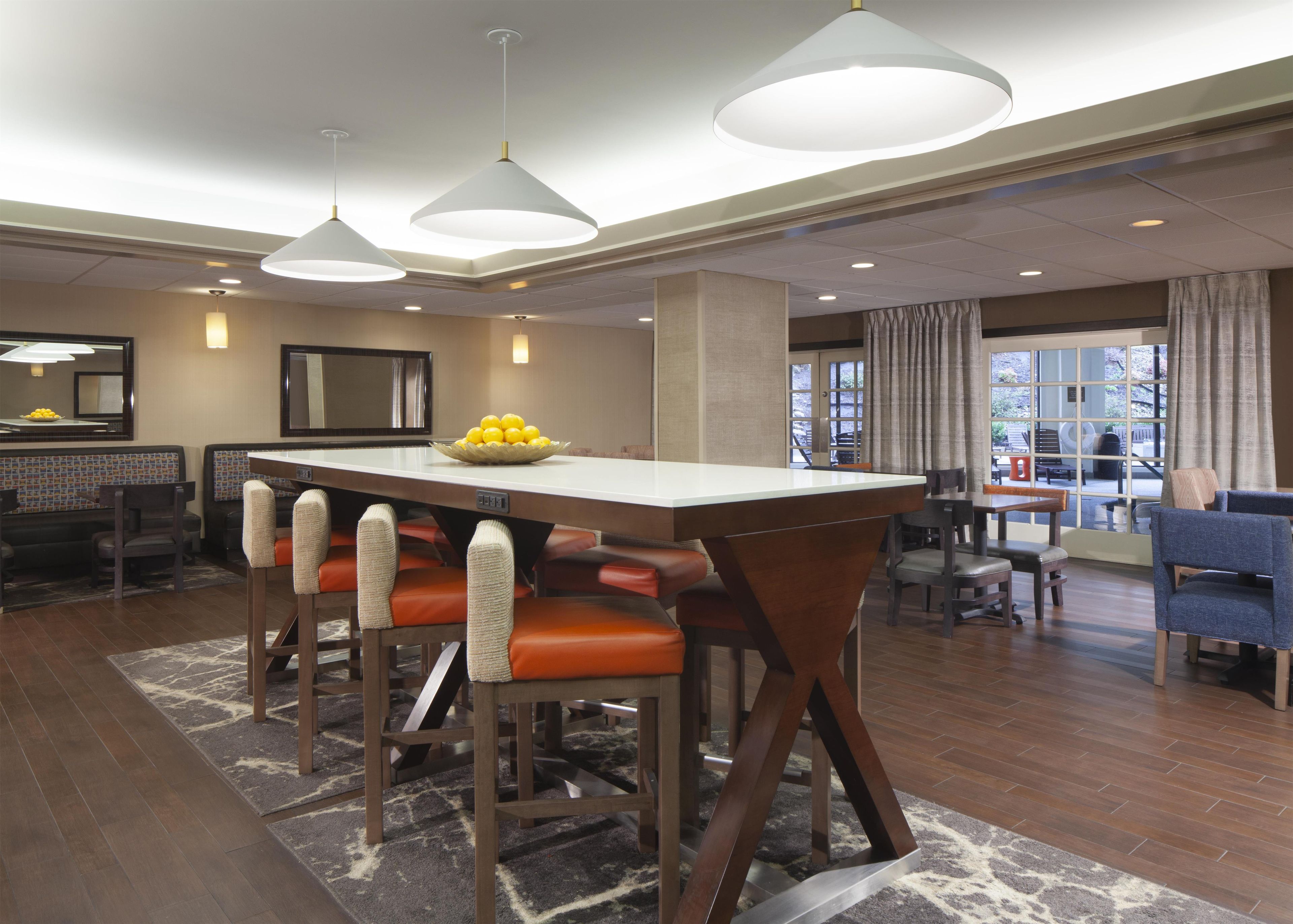 A modern dining area with a central island, bar stools, and pendant lighting.