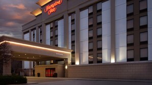 Een groot hotel met een opvallend 'Hampton Inn' bord en een welkomstingang.