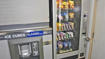 A vending machine with a sign for ice cubes and a variety of snacks.