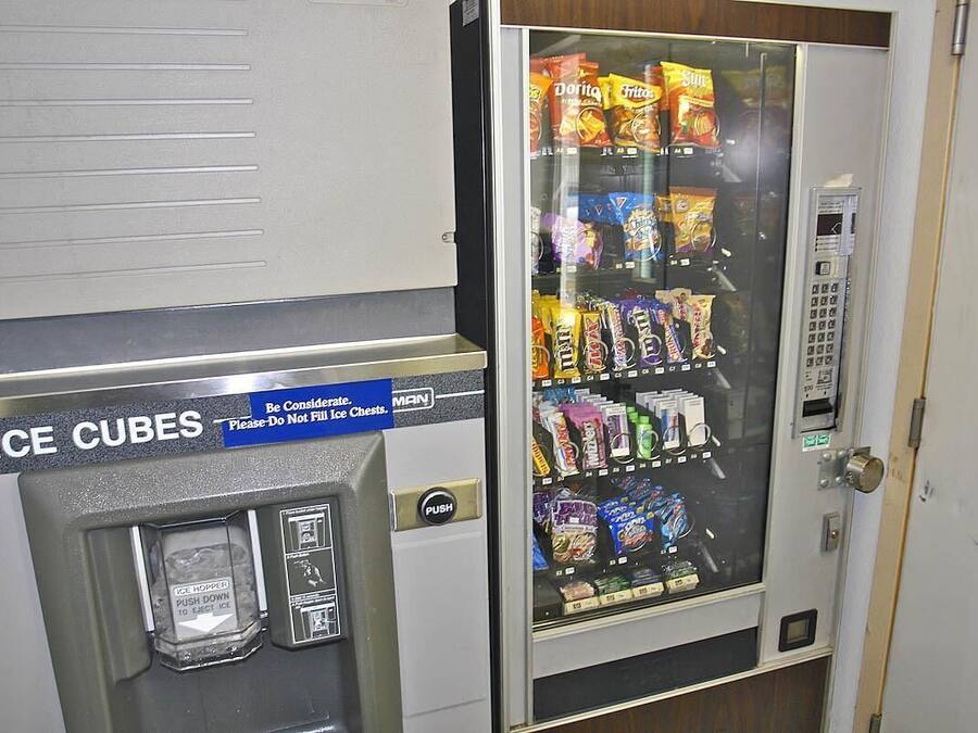 A vending machine with a sign for ice cubes and a variety of snacks.