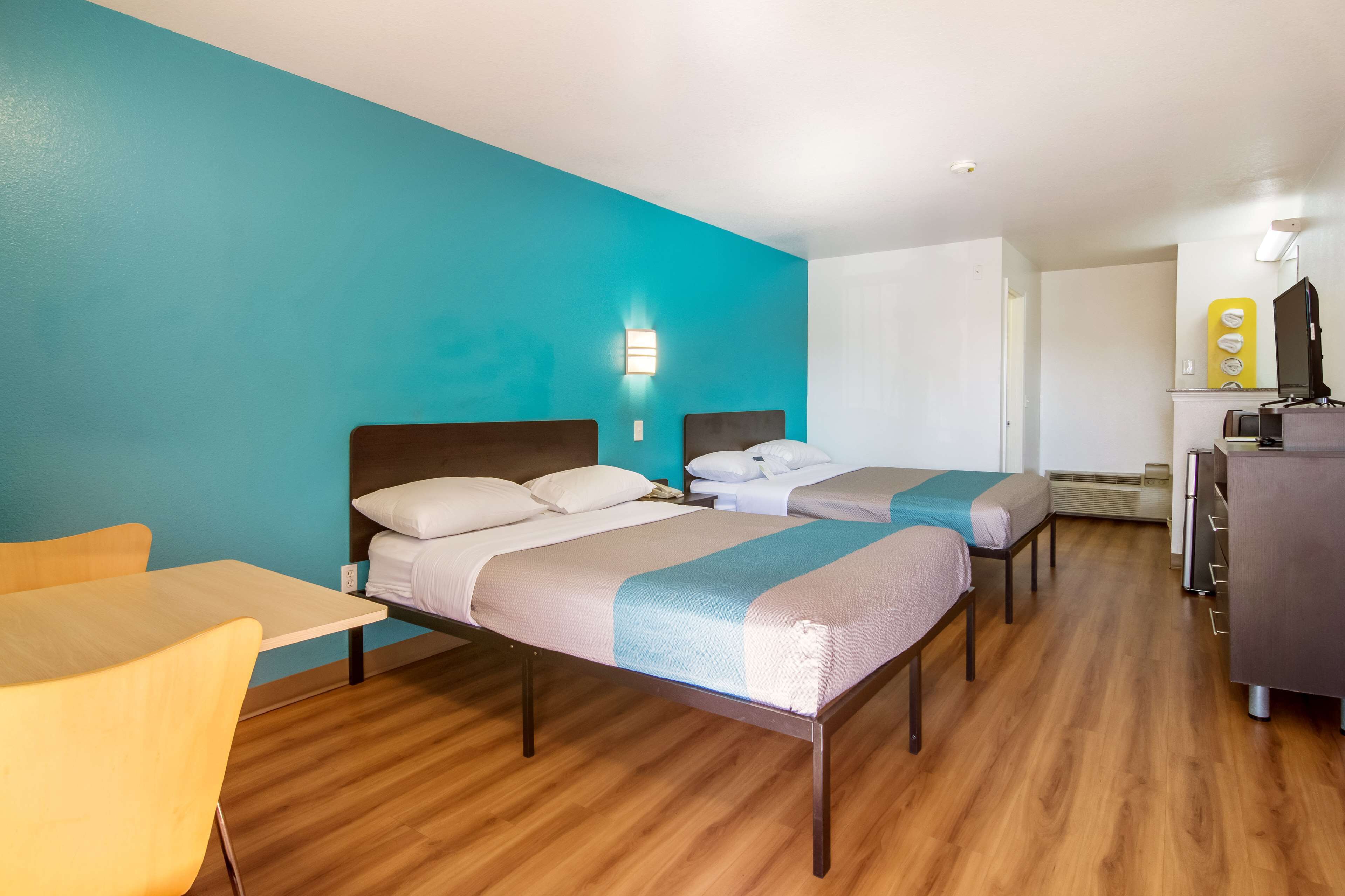 A hotel room with two beds, a desk, and a chair.