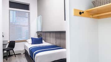 Et moderne hotelværelse med seng, skrivebord og vindue med persienner.