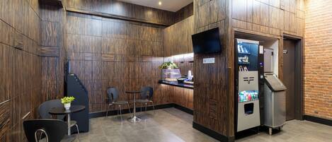 A modern kitchen with wooden paneling, a coffee machine, and a seating area with chairs and a table.