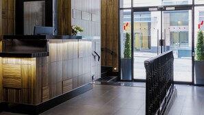 Una hall d'hotel moderna con scrivania della reception, illuminazione a sospensione e ingresso in vetro.