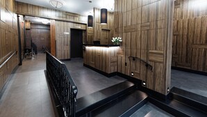 Una hall d'hotel moderna con pannelli in legno, una reception e una scala.