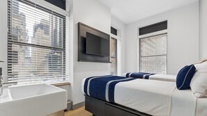 Una camera da letto moderna con un letto, una TV a parete e una finestra con persiane.