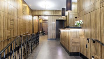 Un moderno vestíbulo de hotel con paneles de madera, una recepción y una escalera.