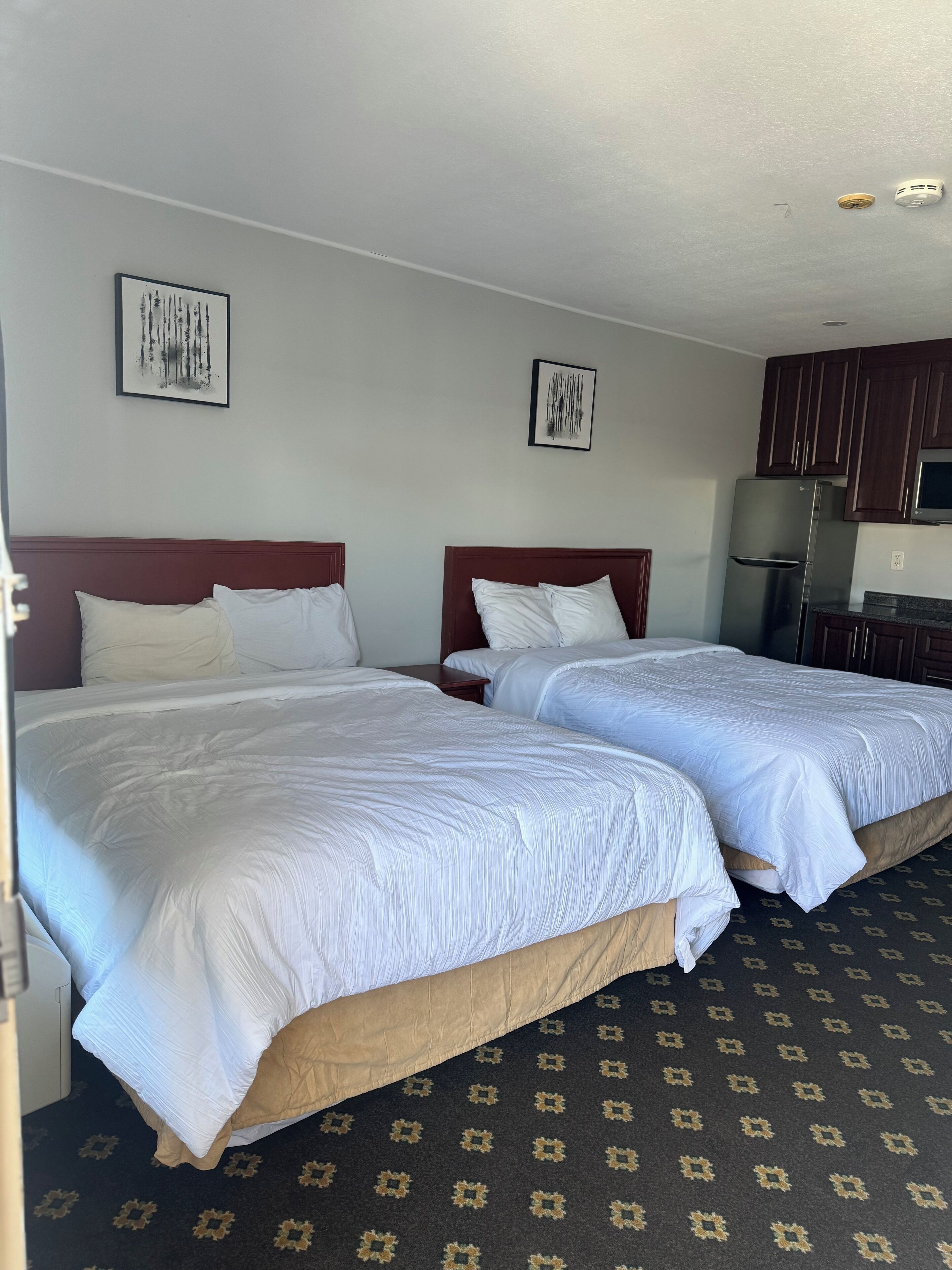 A hotel room with two beds, a refrigerator, and a microwave.