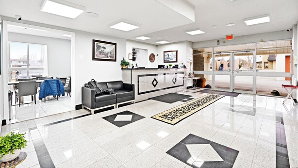 A modern hotel lobby with a reception desk, seating area, and a view of the street.