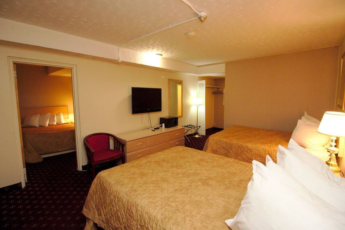 A hotel room with two beds, a TV, a desk, a chair, and a mirror.