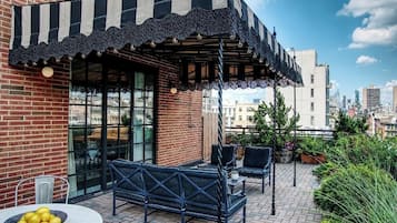 Une terrasse extérieure avec des sièges, une table décorée de citrons et une vue sur le panorama urbain.