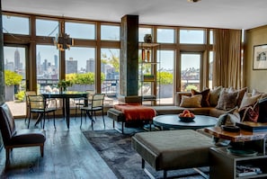 Enjoy a panoramic city view from the large window in this stylish living room, featuring a sofa, chairs, and coffee table.