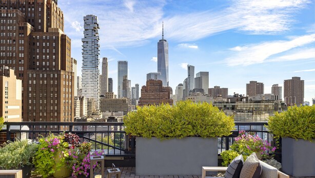 Eine Dachterrasse mit Sitzgelegenheiten, einem Blumenbeet und Blick auf den Stadt-Horizont, einschließlich des One World Trade Center.