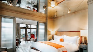 Une chambre d’hôtel moderne dotée d’un grand lit, d’un bureau et offrant une vue sur la ville grâce à de larges fenêtres.