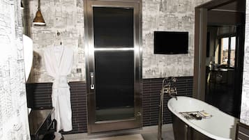 Un baño con una bañera grande, un perchero con bata, un inodoro y un espejo.
