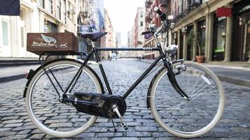 A bicycle with a delivery box labeled "Bose Grand Hotel" parked on a cobblestone street.