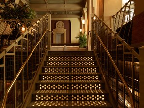 Stunning staircase with a grand, grid-patterned railing and a clock on the landing.