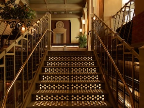Stunning staircase with a grand, grid-patterned railing and a clock on the landing.
