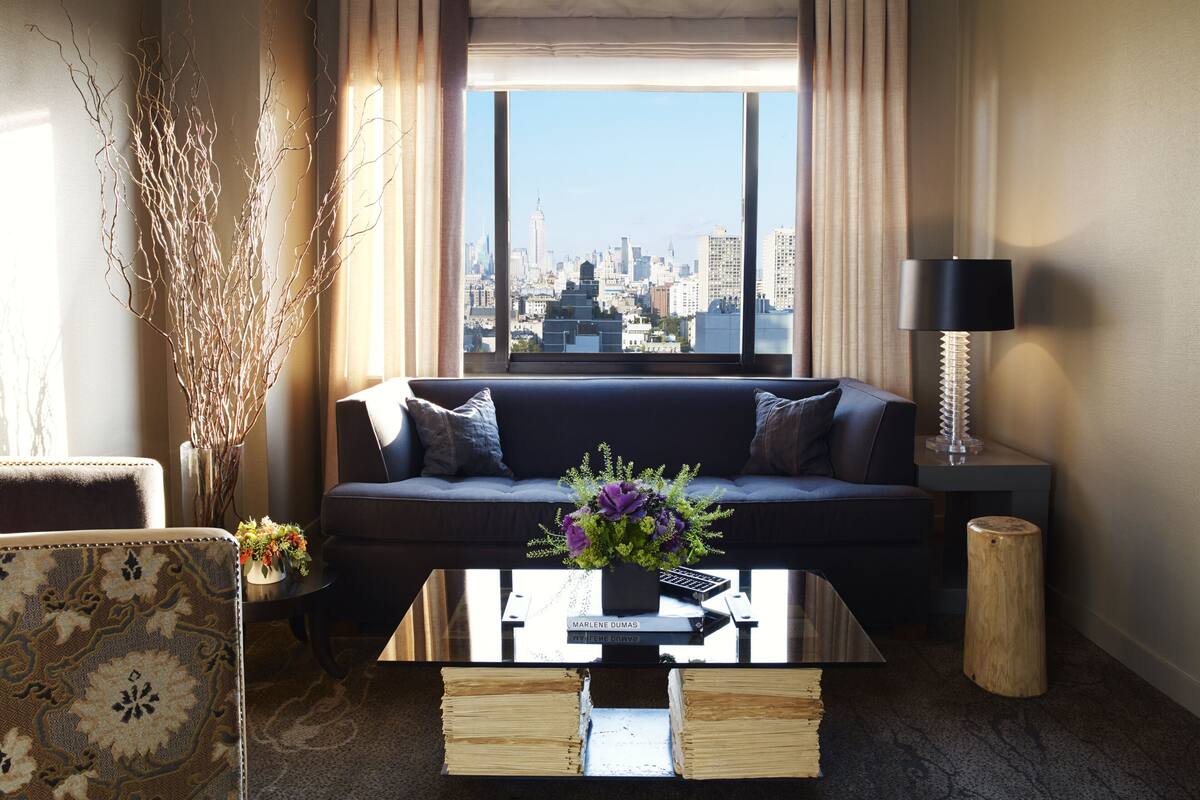 A modern living room with a sofa, coffee table, and a view of a city skyline.