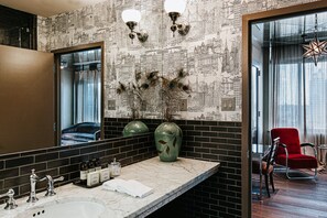 Reflect on the city view from the comfort of this stylish bathroom, featuring a large mirror, sink, and toiletries.