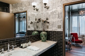 Reflect on the city view from the comfort of this stylish bathroom, featuring a large mirror, sink, and toiletries.