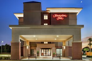 A hotel entrance with a prominent neon sign, a covered entrance area, and a brick facade.
