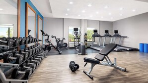 Un gimnasio con equipo de levantamiento de pesas, cintas de correr y máquinas de ejercicio.