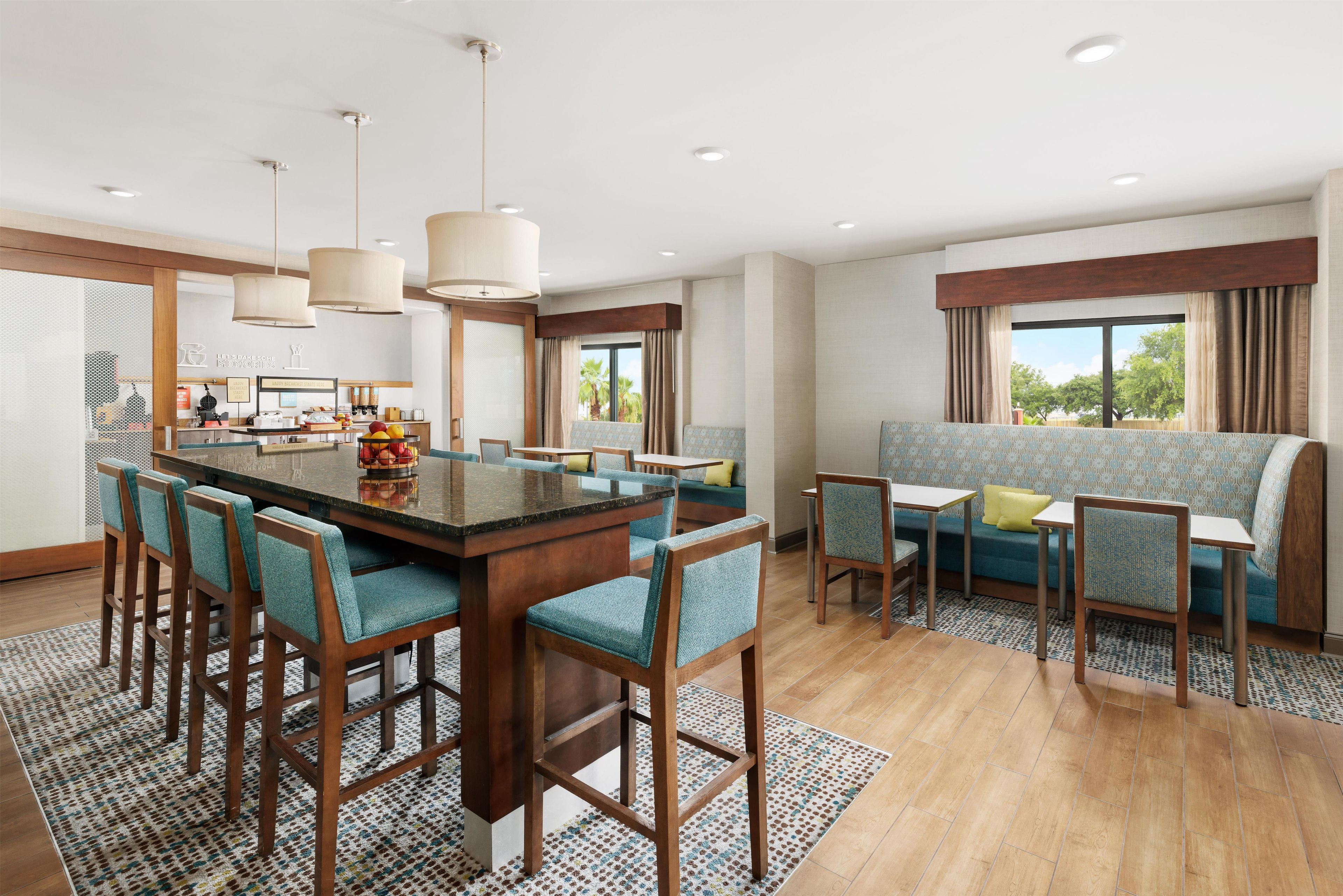 A modern hotel room with a central island, seating area, and large windows.