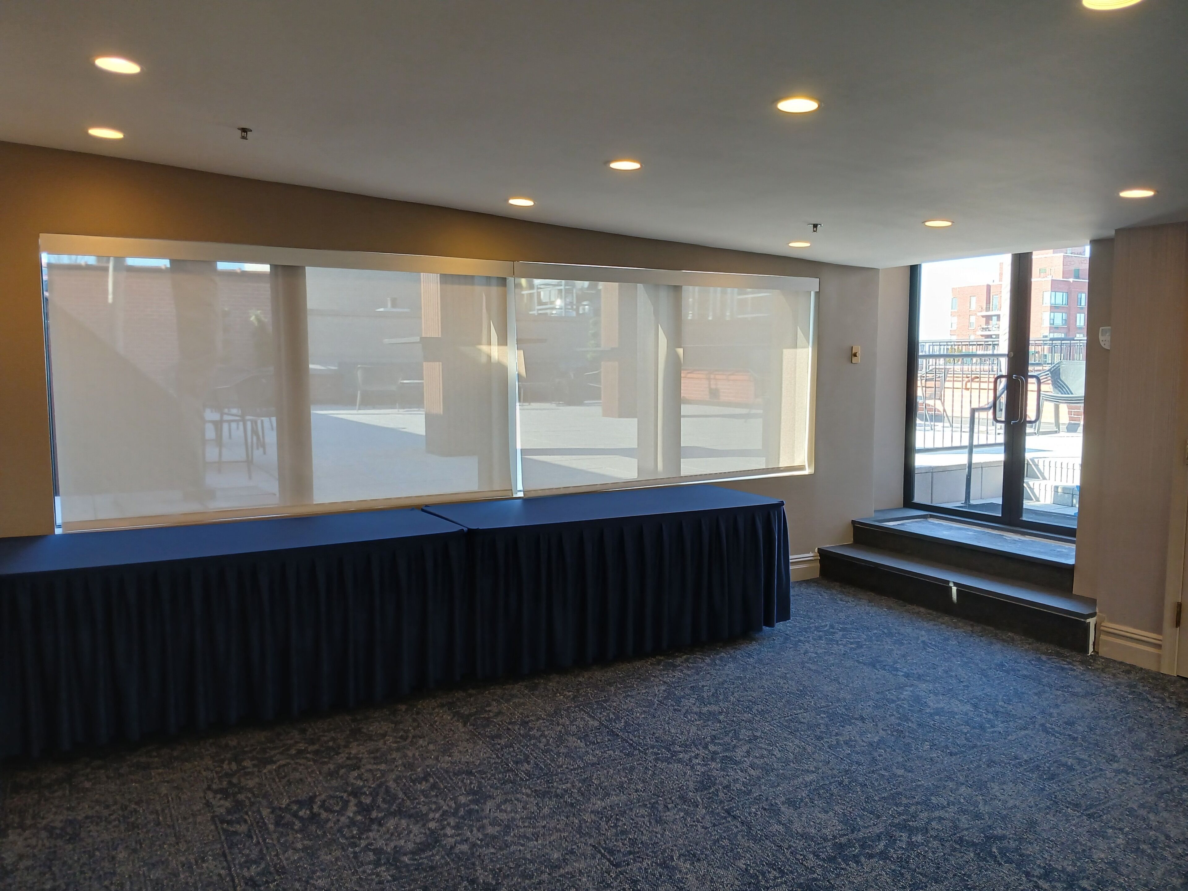 Un salón de conferencias con una gran mesa, alfombra azul y vistas al exterior.