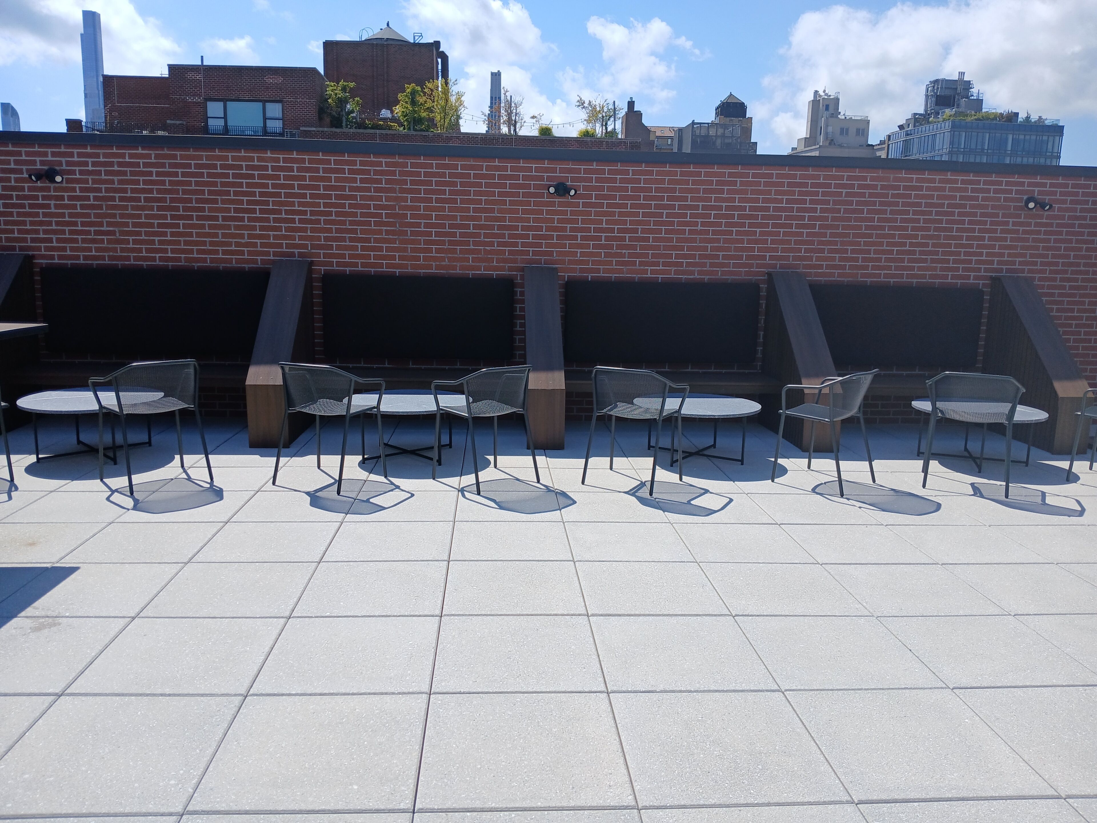 A rooftop patio with outdoor seating and a brick wall.