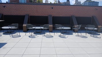 Una terraza en la azotea con mobiliario exterior y un muro de ladrillo.