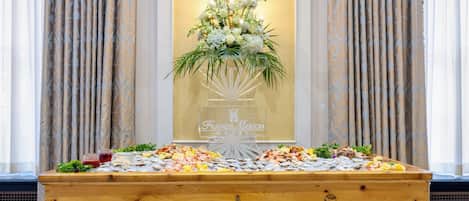 Een houten buffettafel met zeevruchten en een bloemstuk in een hotel.