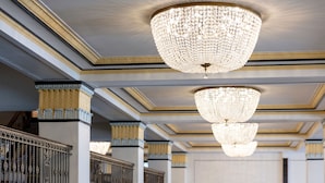 A grand interior with ornate chandeliers, classical columns, and a balcony with intricate railings. - The Francis Marion Hotel (Charleston)