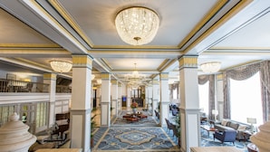 A grand hallway with a patterned floor, chandeliers, and seating areas. - The Francis Marion Hotel (Charleston)