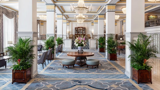 A grand lobby with a central round table, seating, and potted plants. - The Francis Marion Hotel (Charleston)