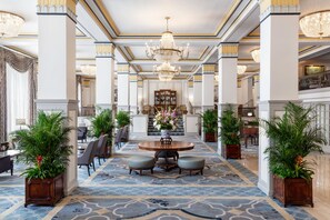 A grand lobby with a central round table, seating, and potted plants. - The Francis Marion Hotel (Charleston)