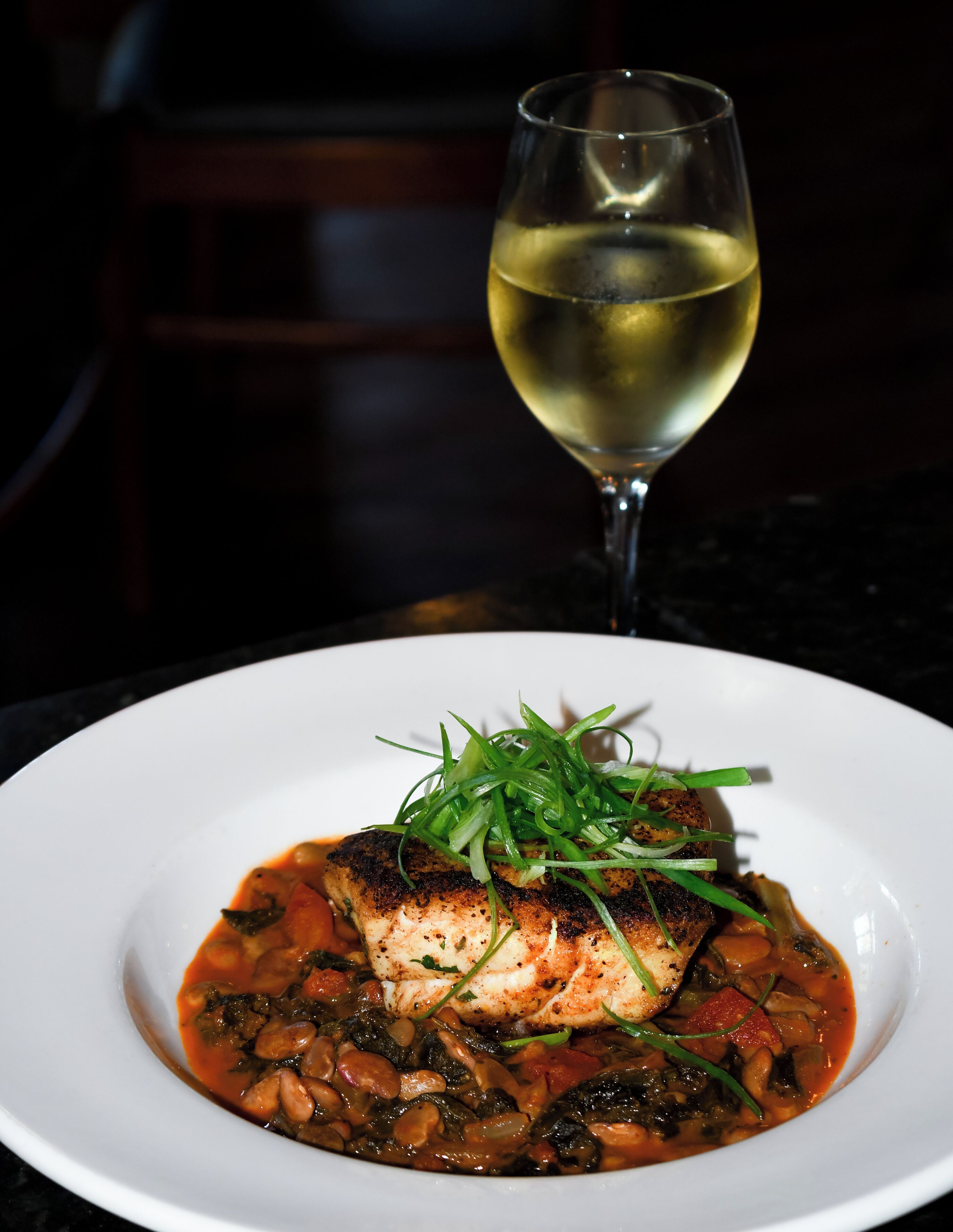 A plate of food with a glass of white wine.