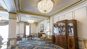 A grand lobby with a large chandelier, a wooden cabinet with glass doors, and a patterned carpet. - The Francis Marion Hotel (Charleston)