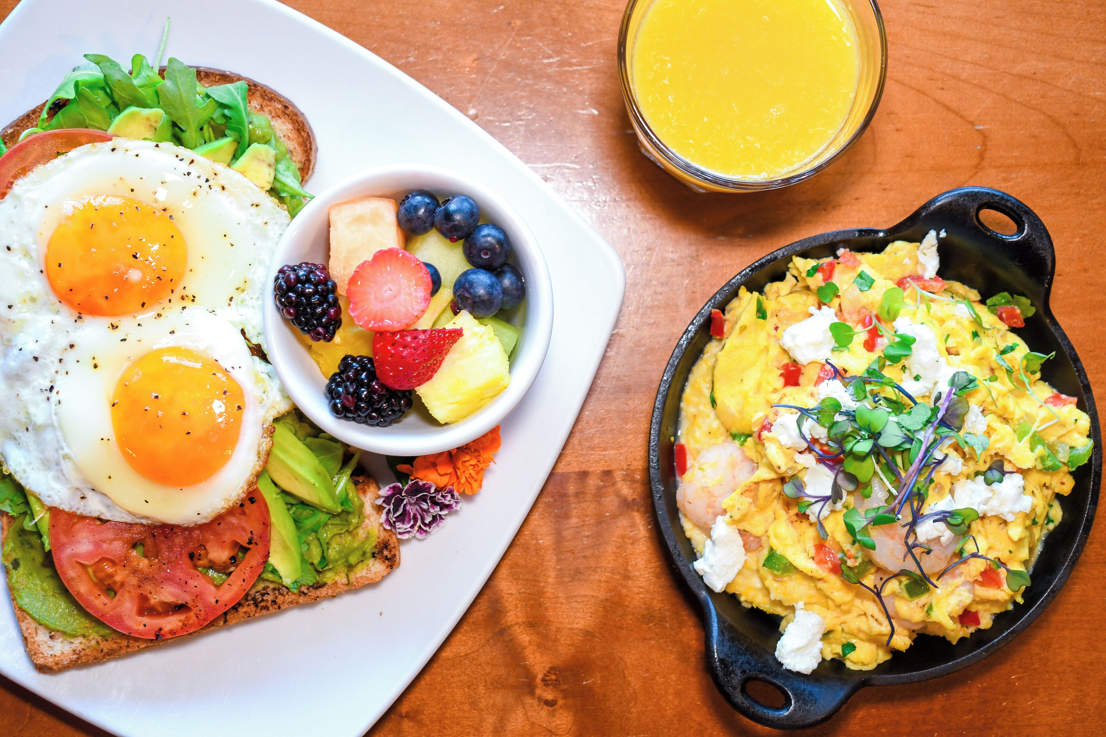 A breakfast plate with eggs, avocado, tomato, and a side salad.
