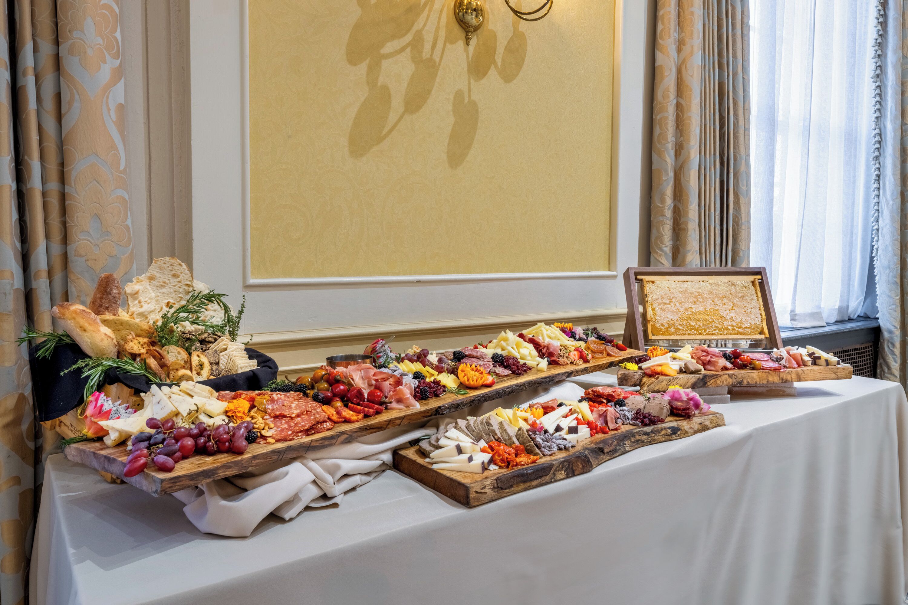 A buffet table with an assortment of cheeses, meats, and fruits.