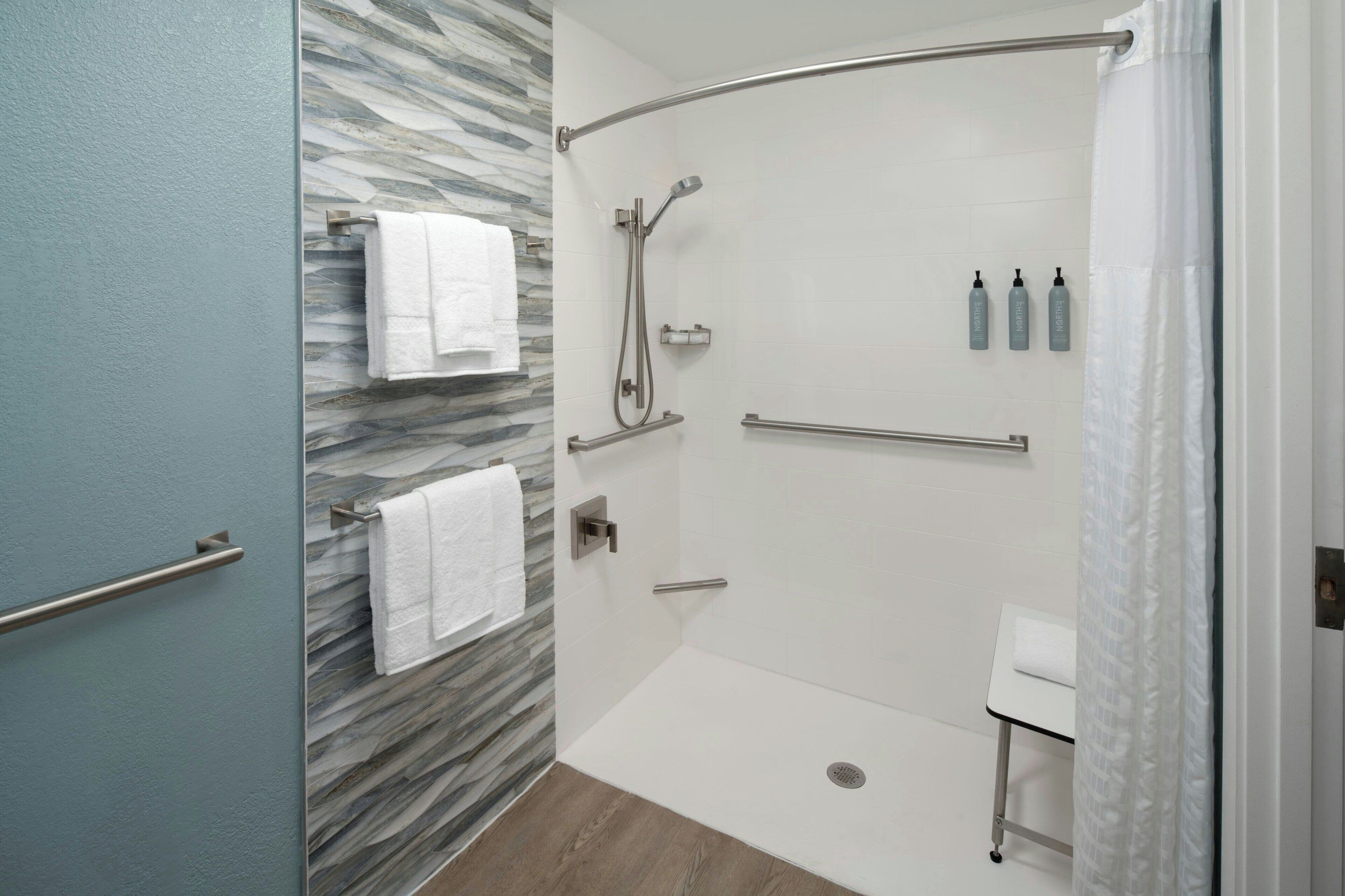 Ein modernes Badezimmer mit einer Duschkabine aus Glas, einem weißen Waschbecken und einer Marmorwand.
