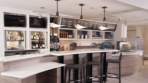 A modern bar area with a white countertop, black bar stools, and a menu board above.